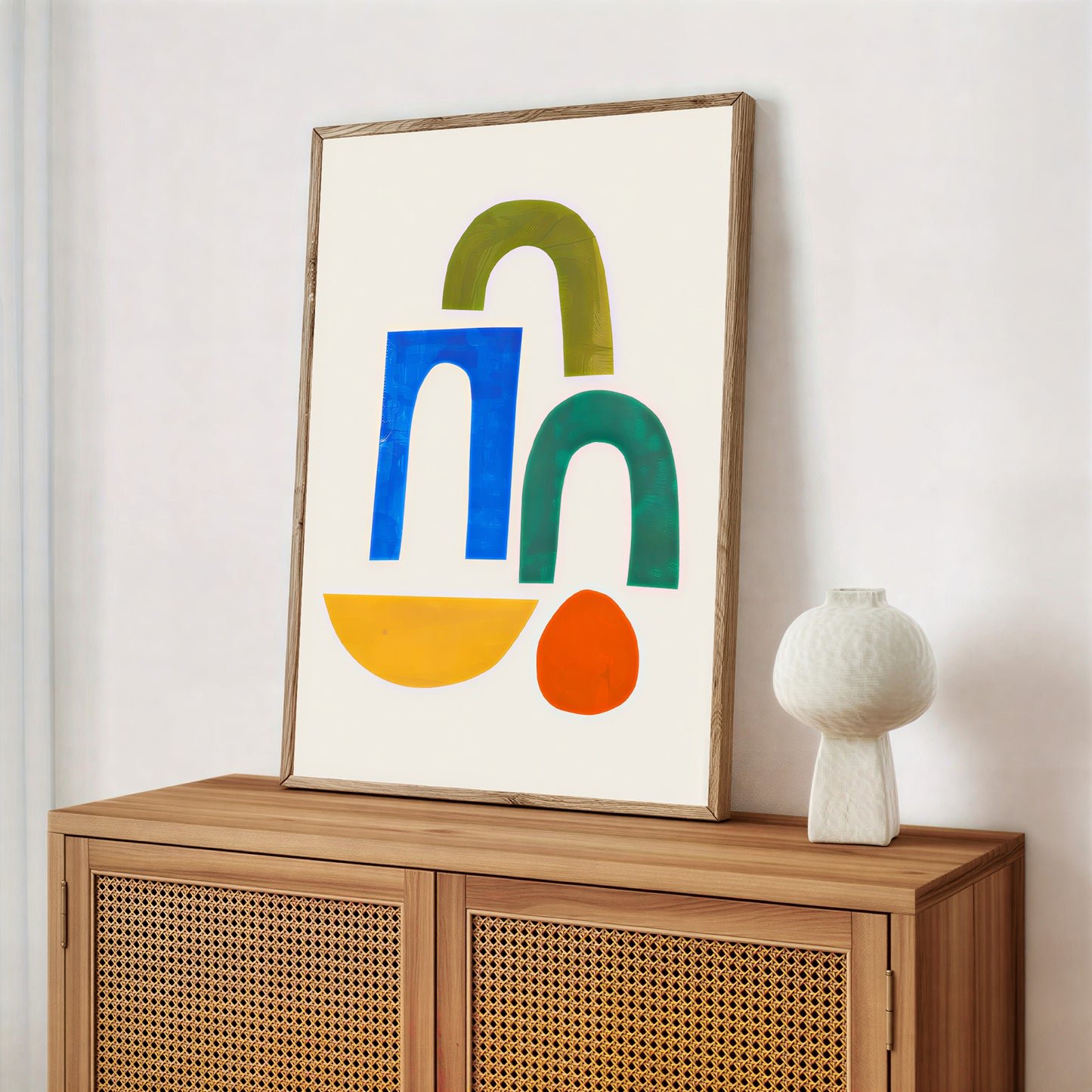 Framed abstract art with colorful shapes on a wooden cabinet against a white wall.