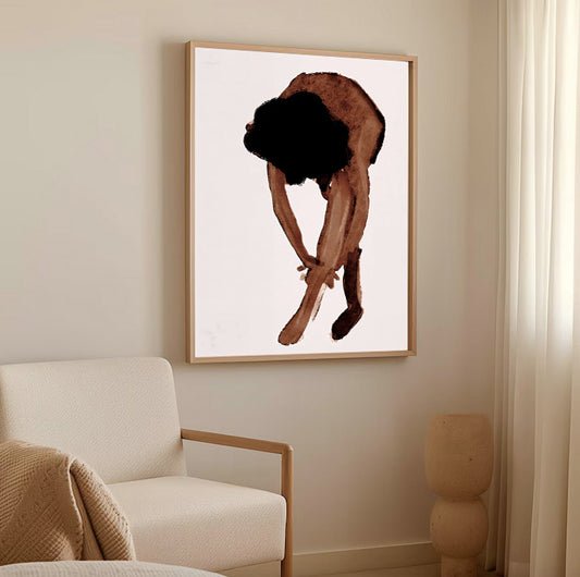 Framed artwork of a person tying their shoes on a wall in a living room.Abstract watercolor figure wall art print
