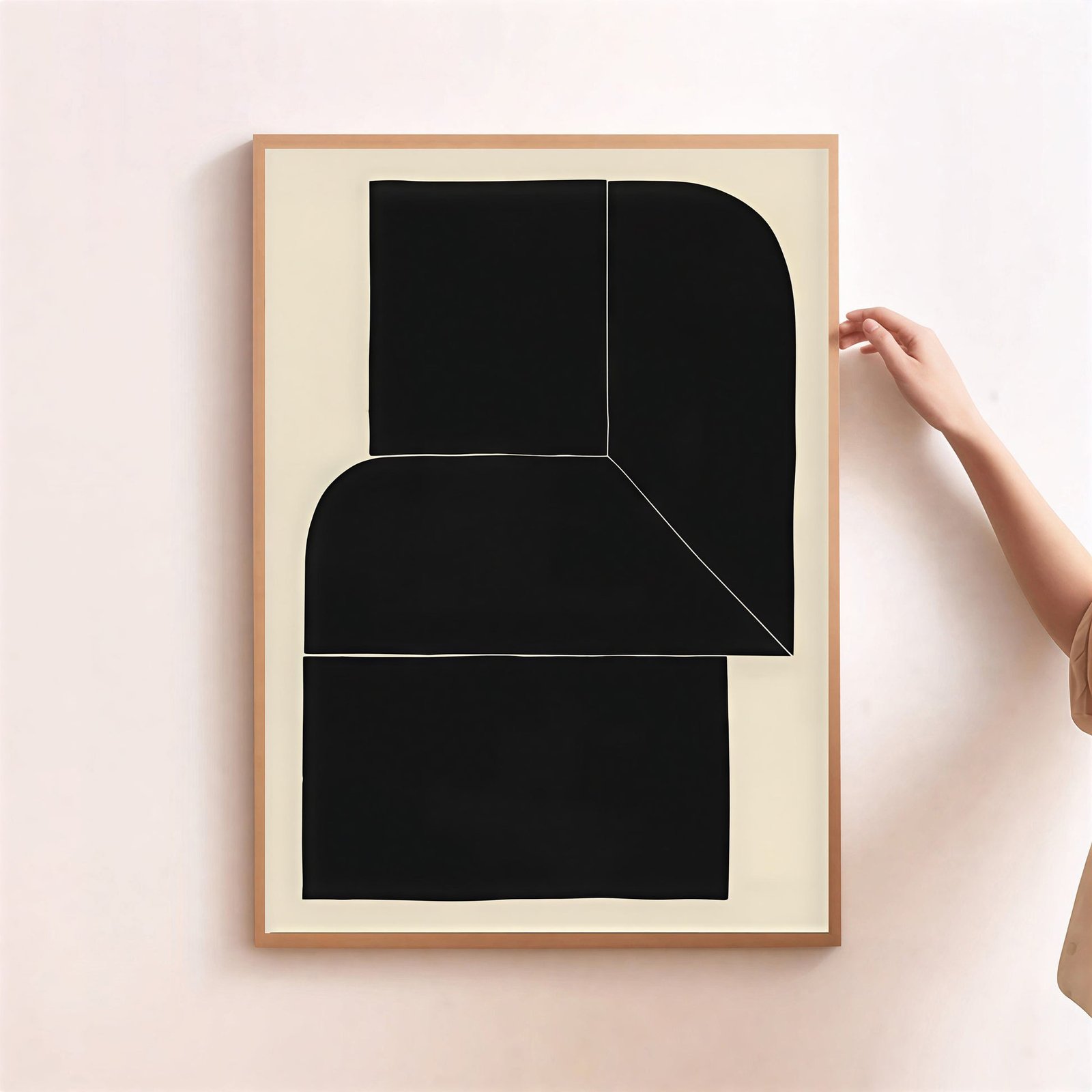 Framed abstract art piece with black shapes on a beige background, held by a person.