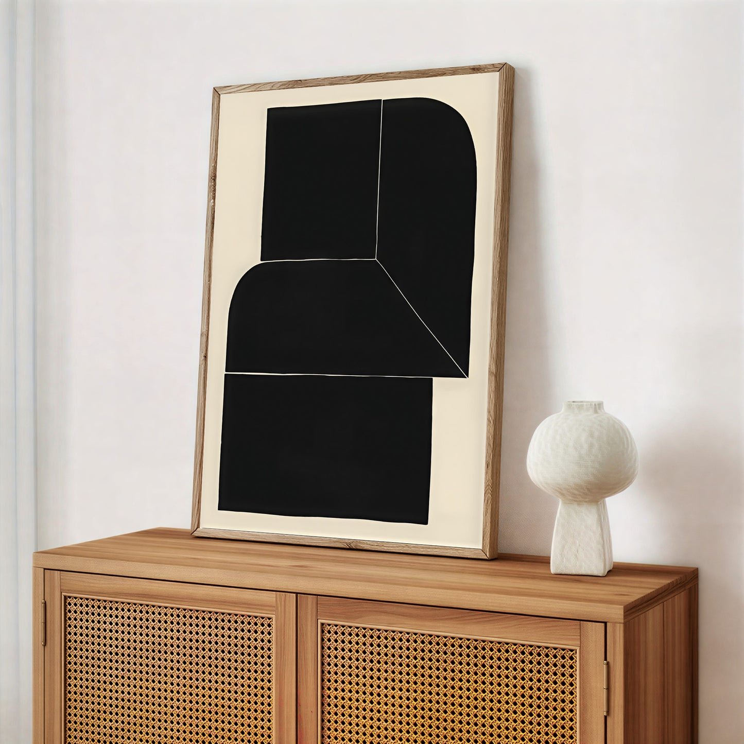 Abstract art piece on a wooden cabinet with a white vase.