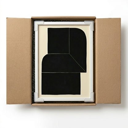 Framed artwork Black Minimalist Abstract Wall Art Print inside an open cardboard box on a white background